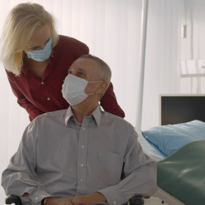 A shop worker wearing a face mask behind a protective screen